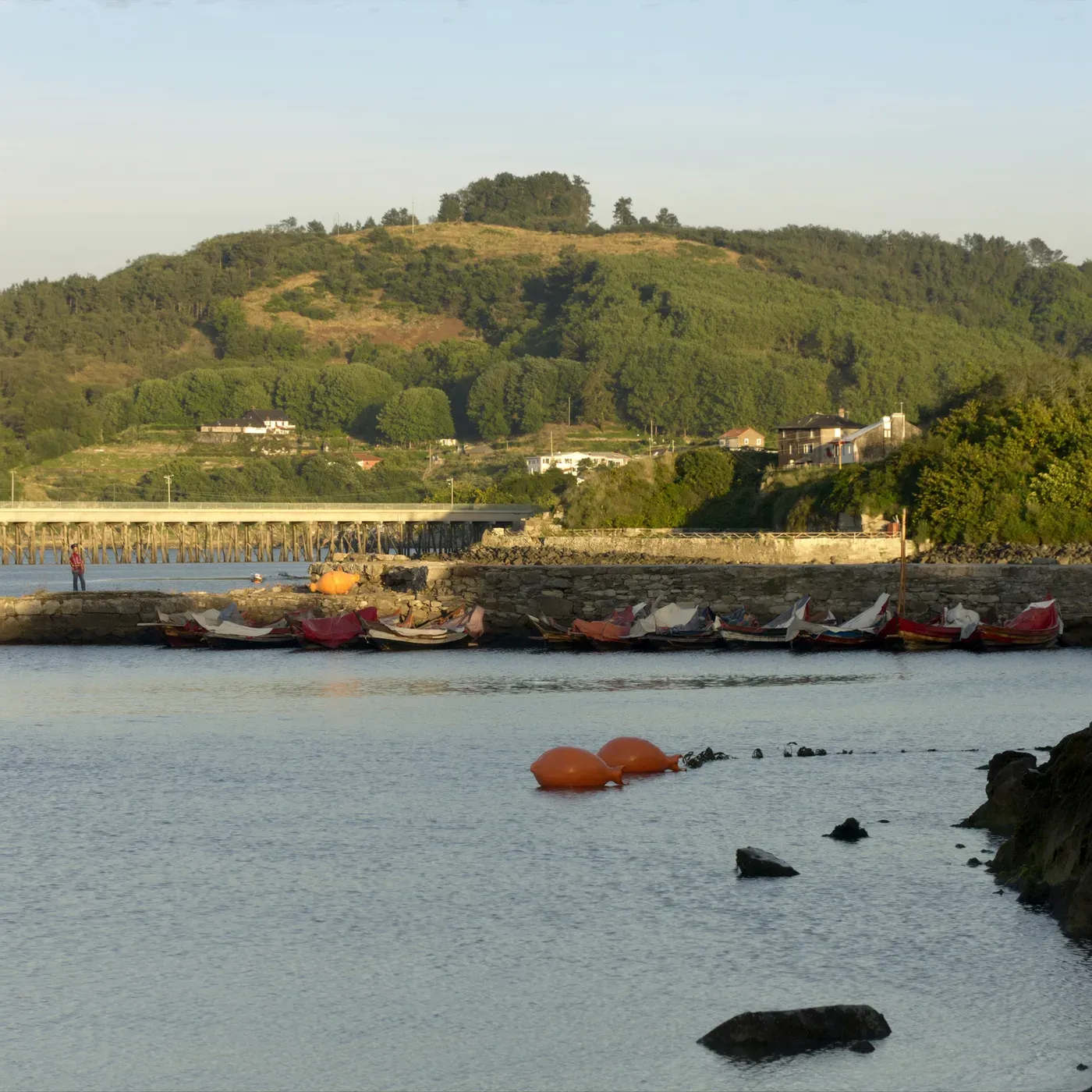 Illustrated coastal scene evoking Spain — the home of La Brújula