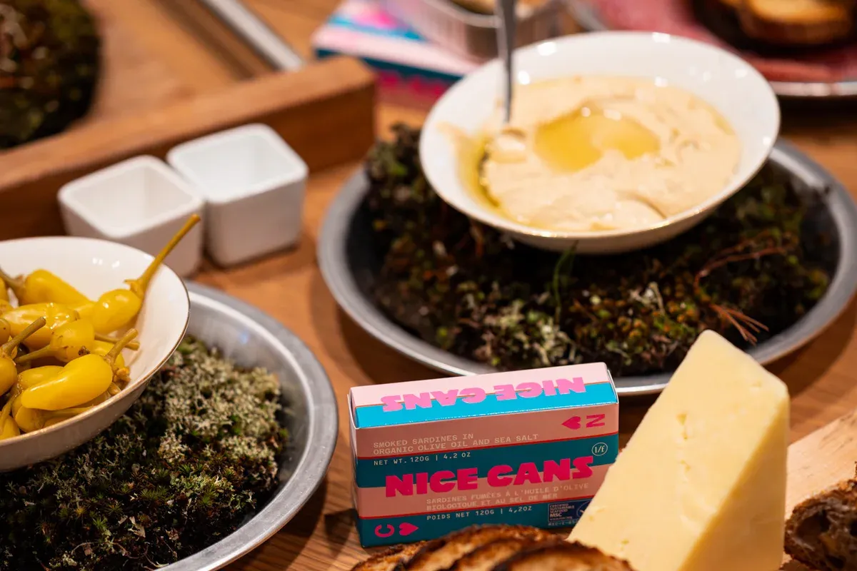 A Nice Cans tin and box among bread, cheese and olives on the launch-event spread